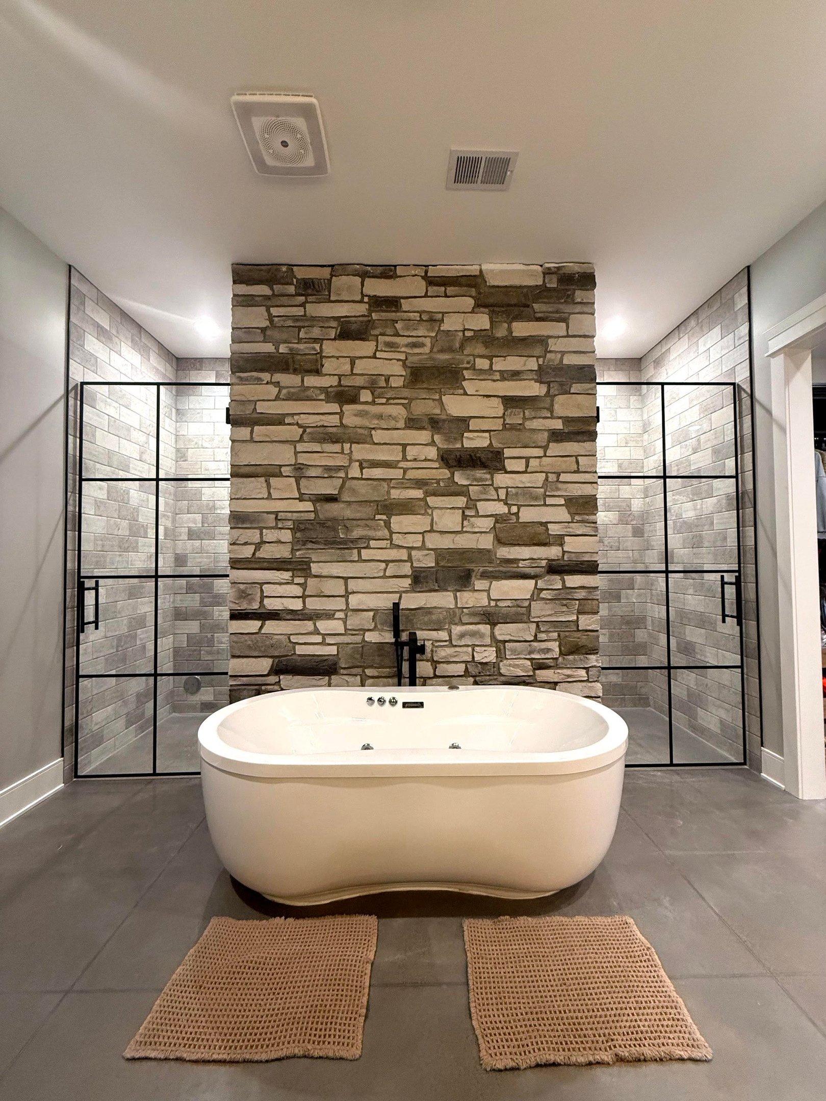 Bathroom with freestanding tub and glass showers