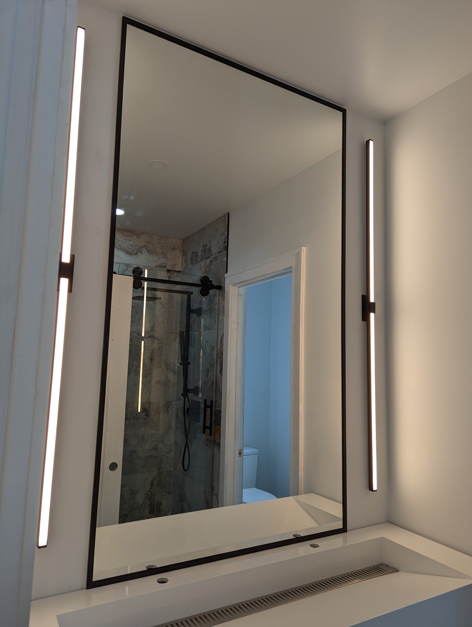 Barn-style glass shower door and illuminated mirror